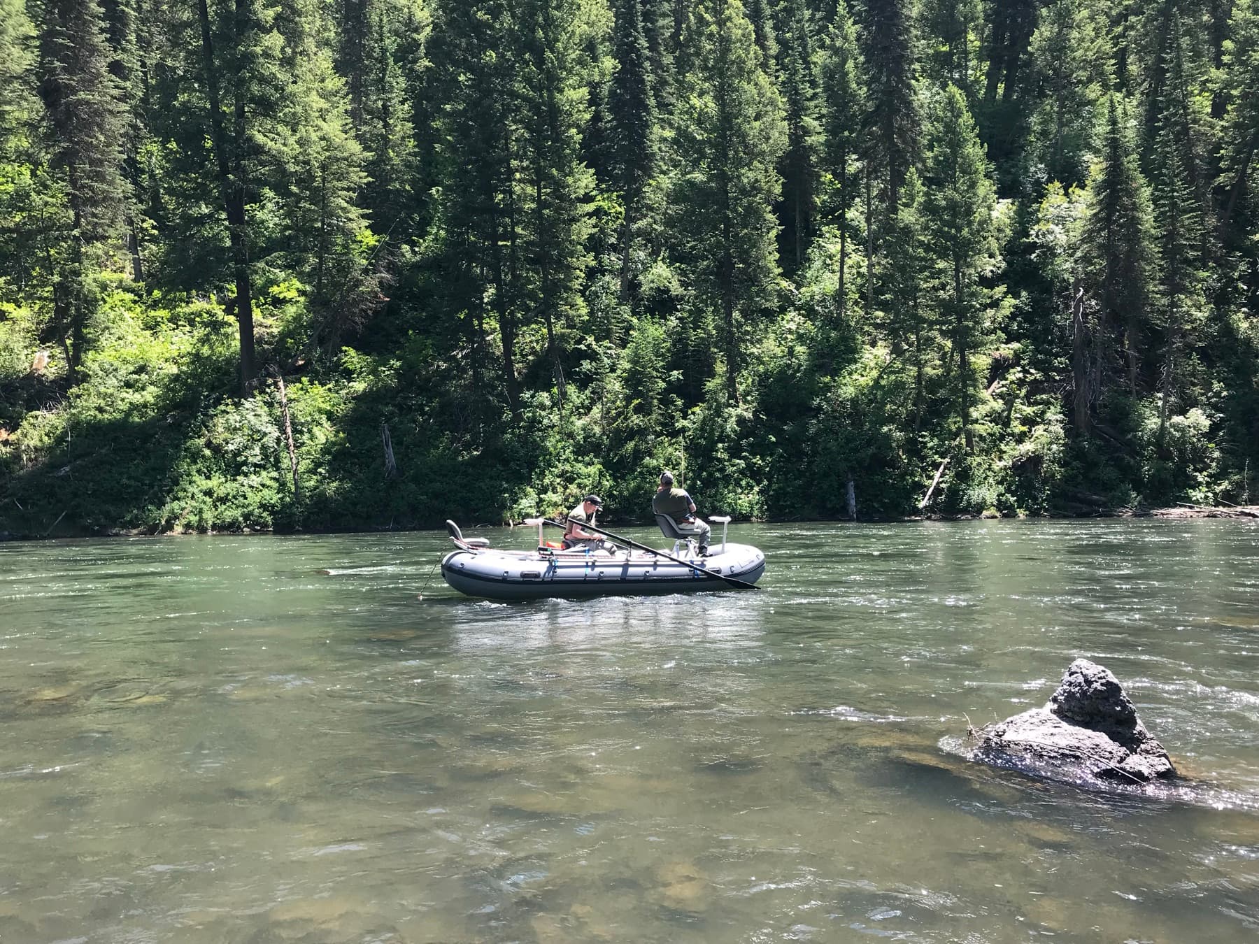 Anglers rafting through a forested canyon stretch