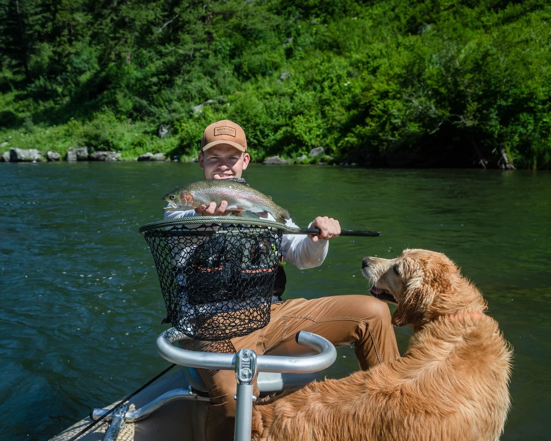 Angler with a rainbow trout and golden retriever on the Henry's Fork