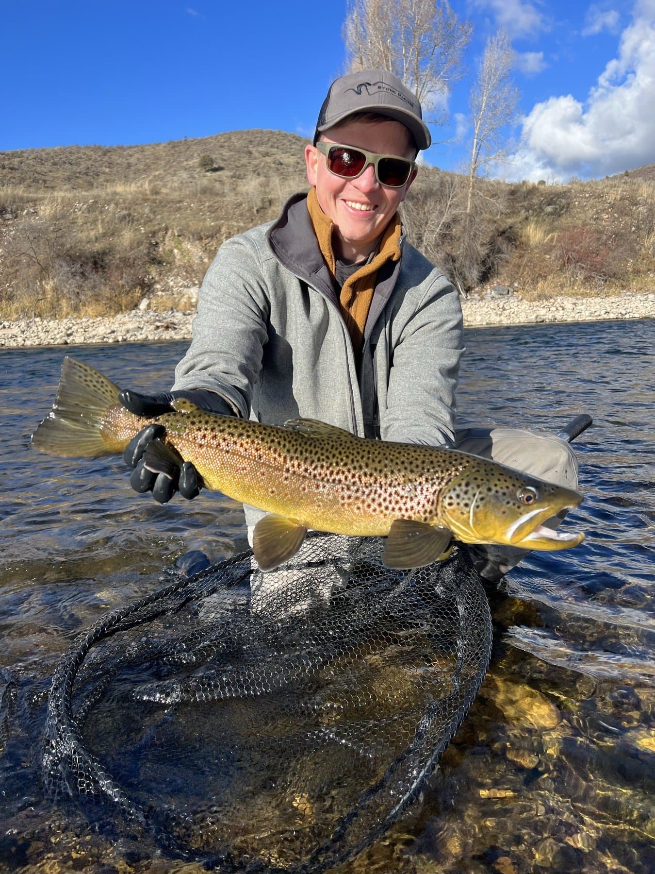 Angler holding a big South Fork brown trout streamside