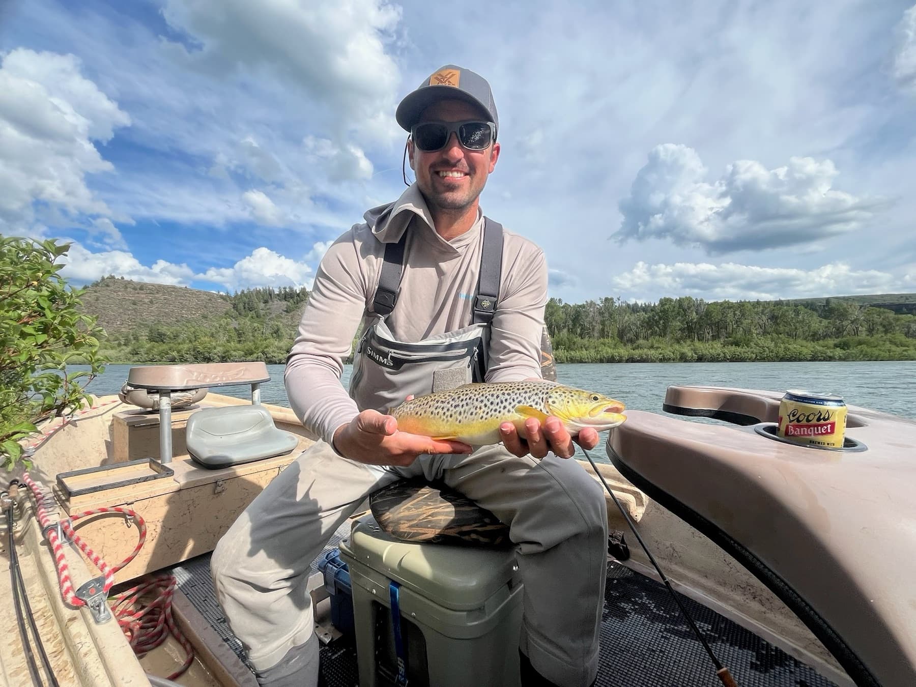 Angler holding a brown trout while relaxing in the drift boat